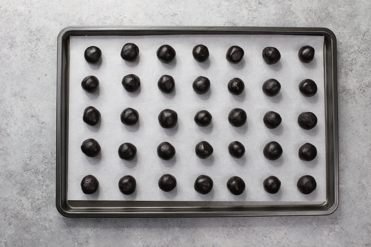 A set of 35 oreo ball fillings on a baking sheet ready to be frozen to firm up