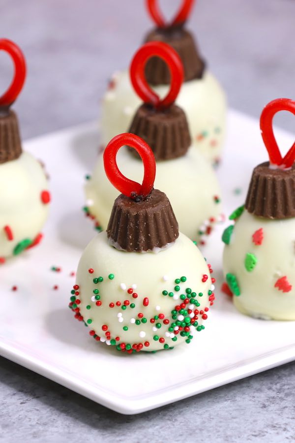 Oreo Truffle Ornaments - adorable bite size treats to make for a holiday party. All you need is oreo cookies, white chocolate, mini Reese's peanut butter cups, red licorice and some nonpareil sprinkles. So much fun and so delicious!