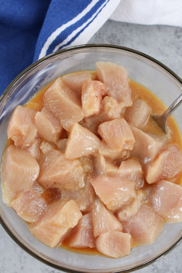 Overhead view of velveting chicken in a clear bowl