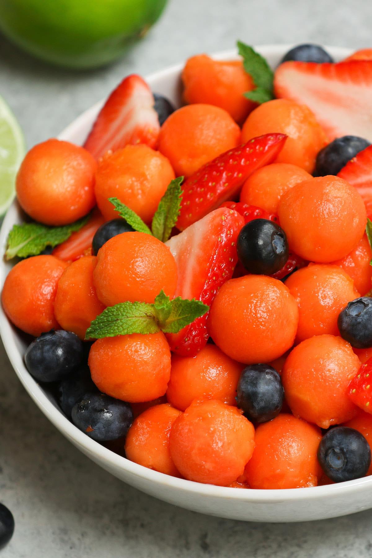 A serving of papaya salad made with freshly cut papaya, sliced strawberries, blueberries and mint for garnish