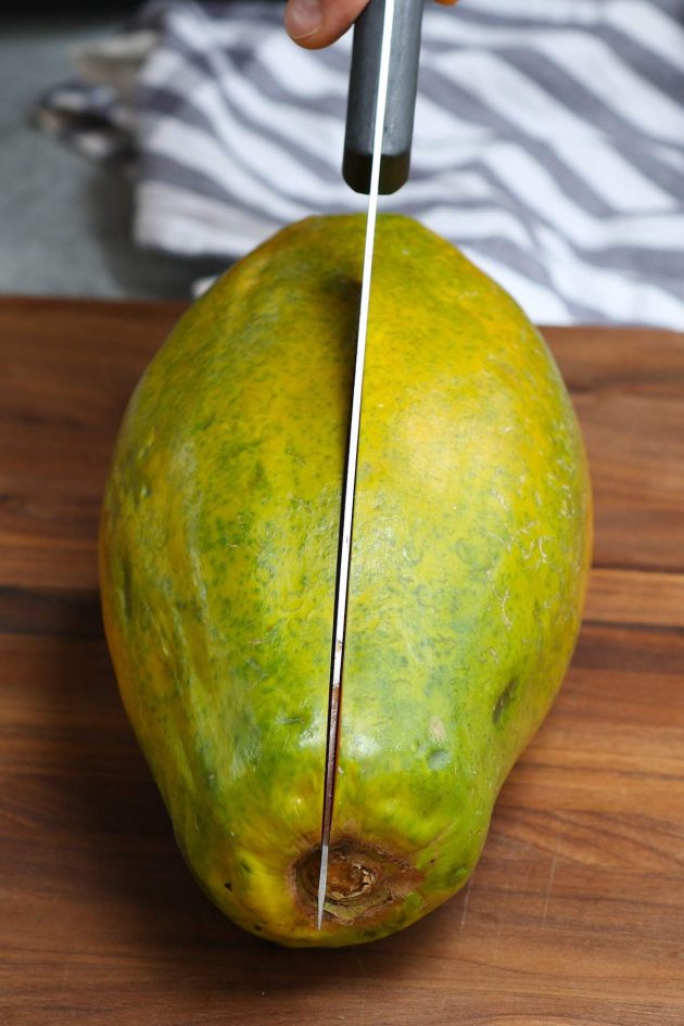 Cutting a papaya in half using a chef's knife