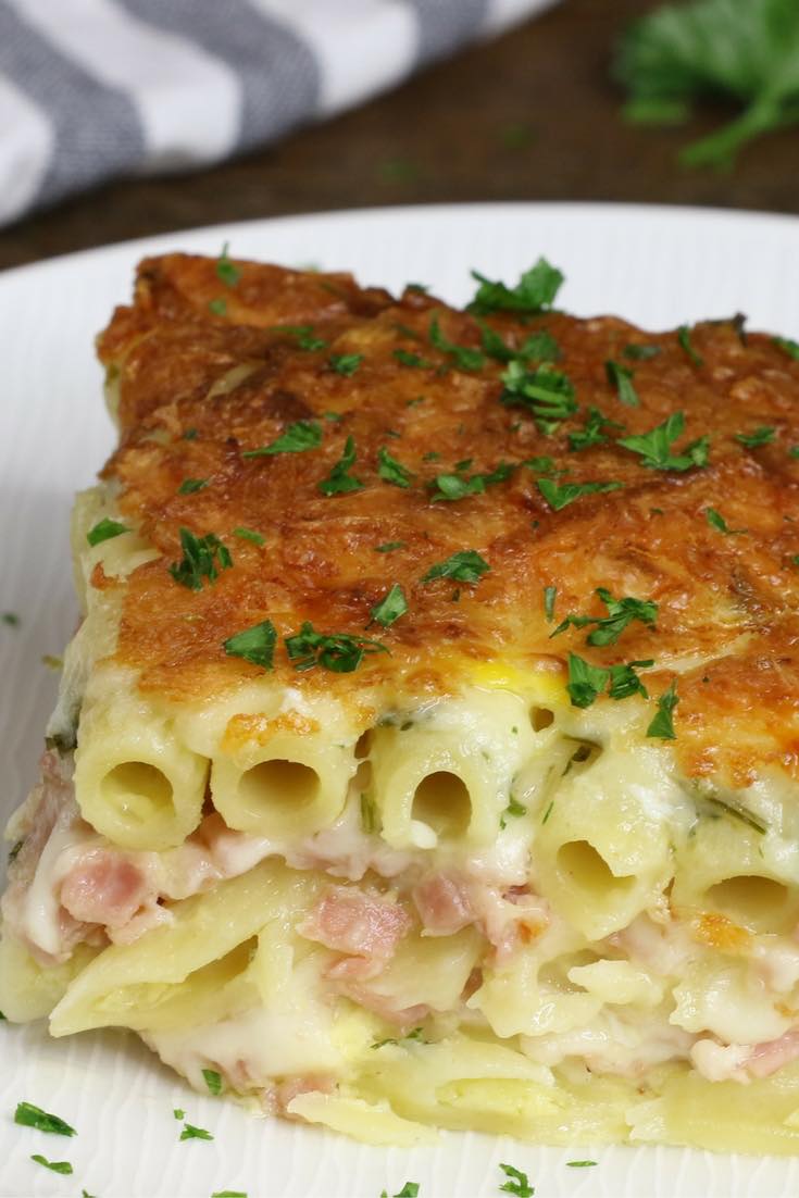A serving of Layered Ham And Cheese Pasta Casserole on a plate. It's a creamy and cheesy layered penne pasta, ham and Swiss cheese baked in the heavy cream and eggs mix. Perfect dinner for a hungry crowd! Quick and easy dinner recipe.