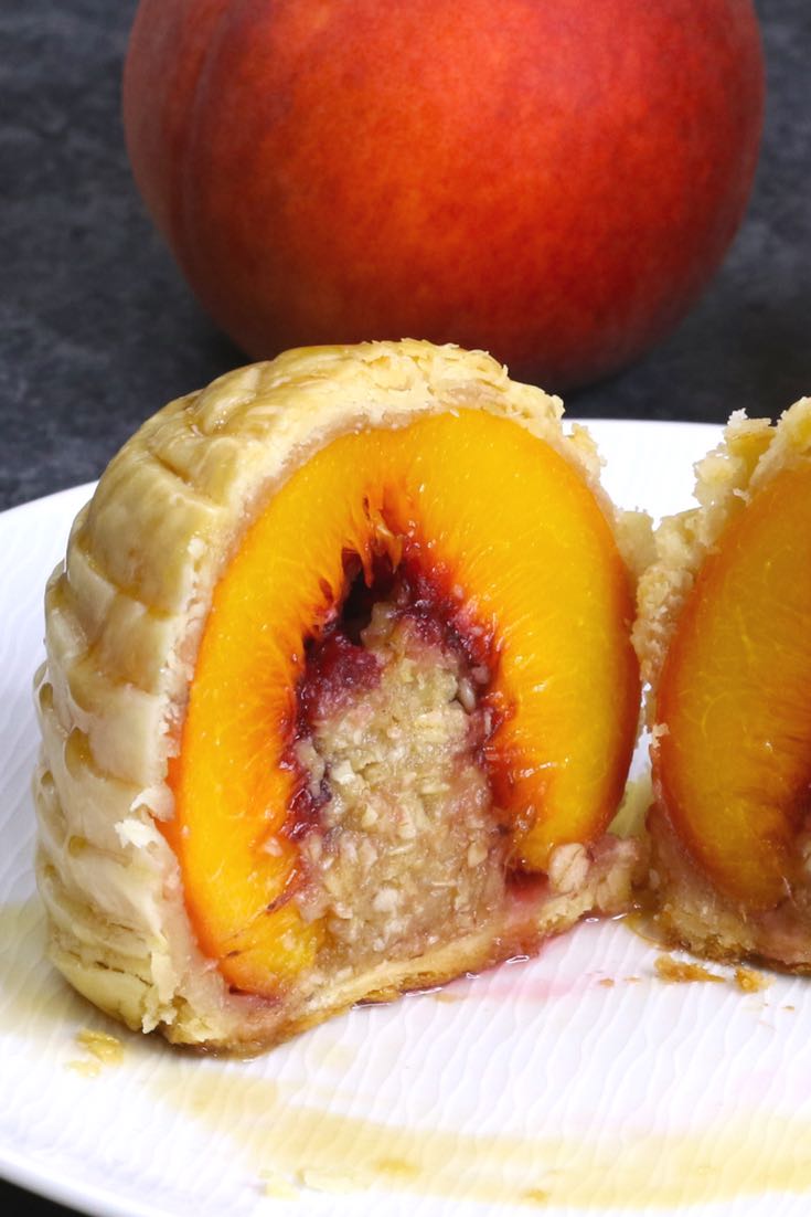 An individual puff pastry peach cobbler sliced in half to show the stuffing in the middle