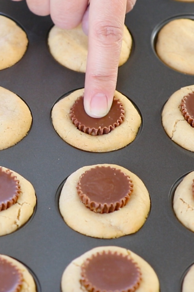 Pressing a mini Reese's peanut butter cup into cookie dough before baking