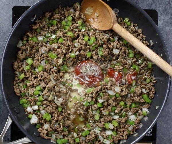 This photo shows adding sauce ingredients to the beef, onion and green pepper mixture to make Philly Cheesesteak