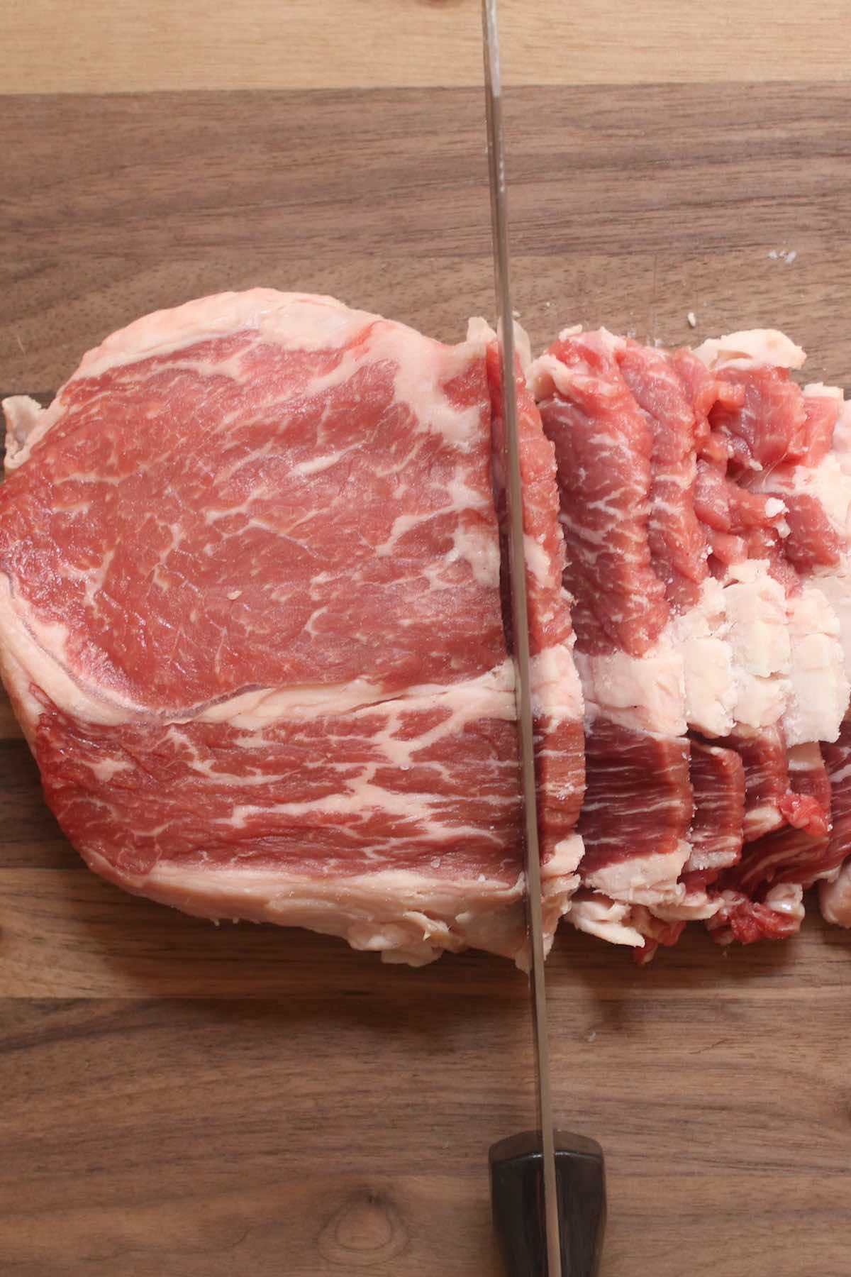 Cut the half-frozen ribeye steak on a cutting board