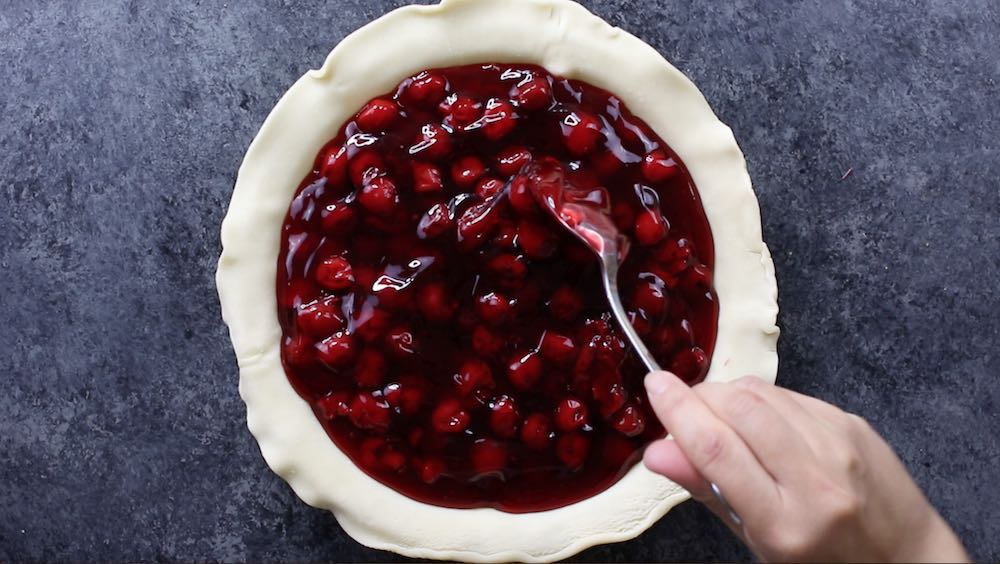 Adding cherry filling to the pie crust