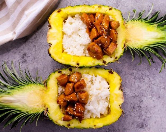 Overhead view of teriyaki chicken served in a half pineapple with rice