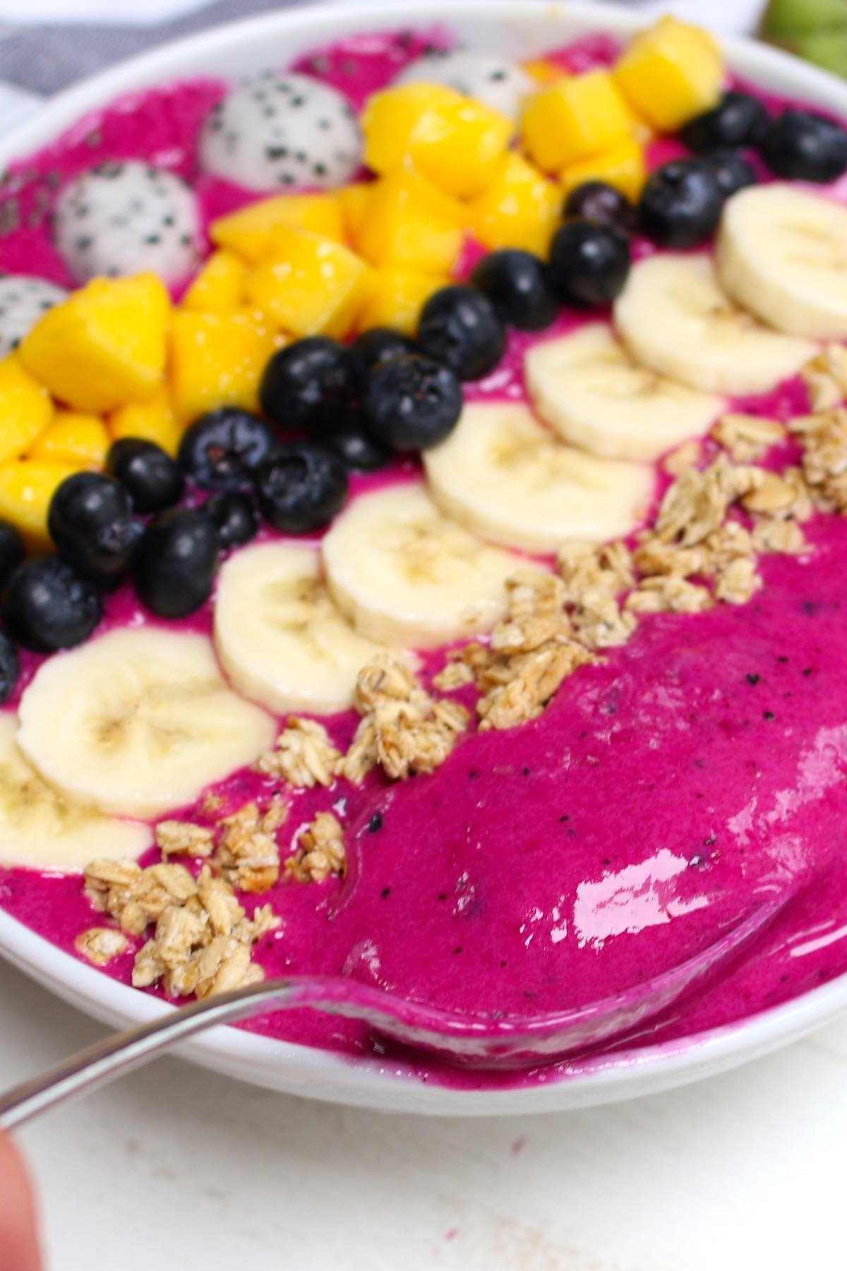 Spooning the smoothie in a pitaya bowl to show the thick texture