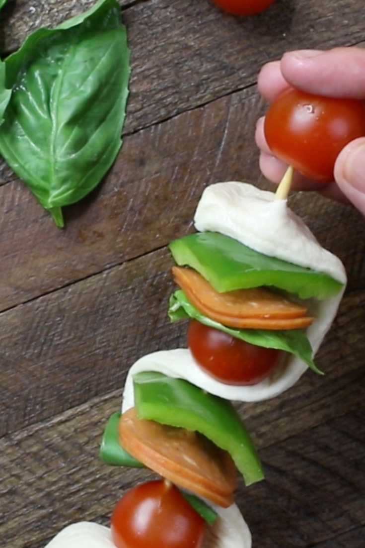 Placing pizza dough and toppings onto a wooden skewer