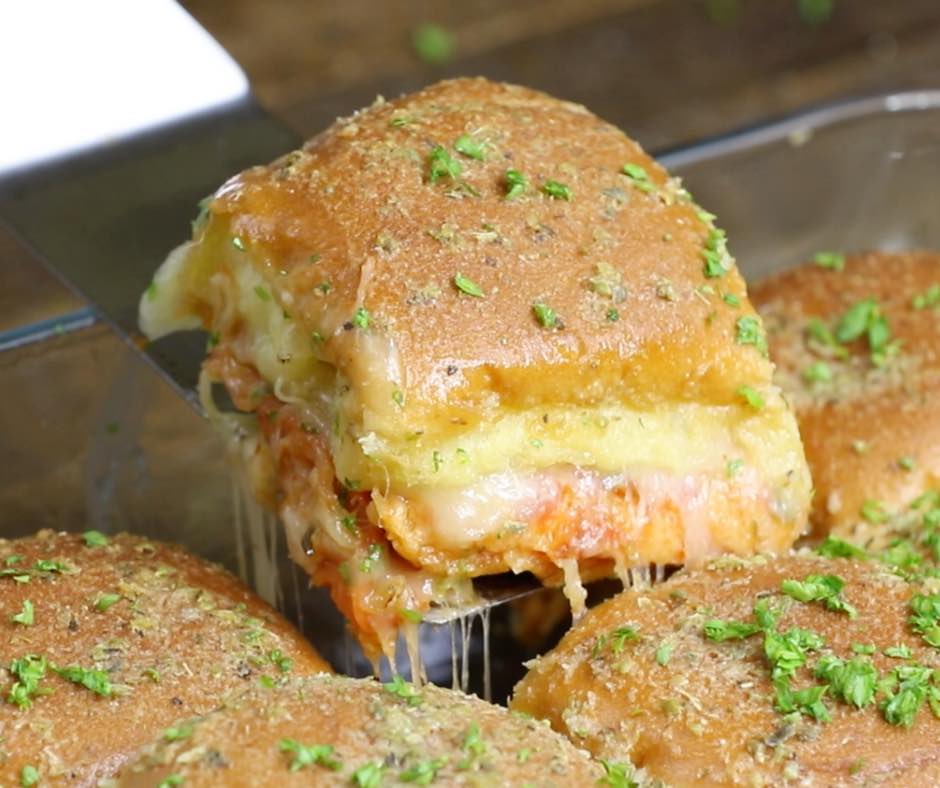 Lifting a pizza slider out of the baking pan with a cheese pull