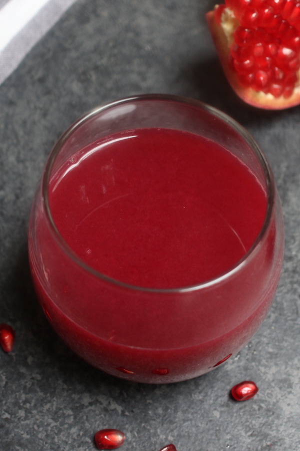 A serving of freshly made pomegranate juice in a stemless wine glass