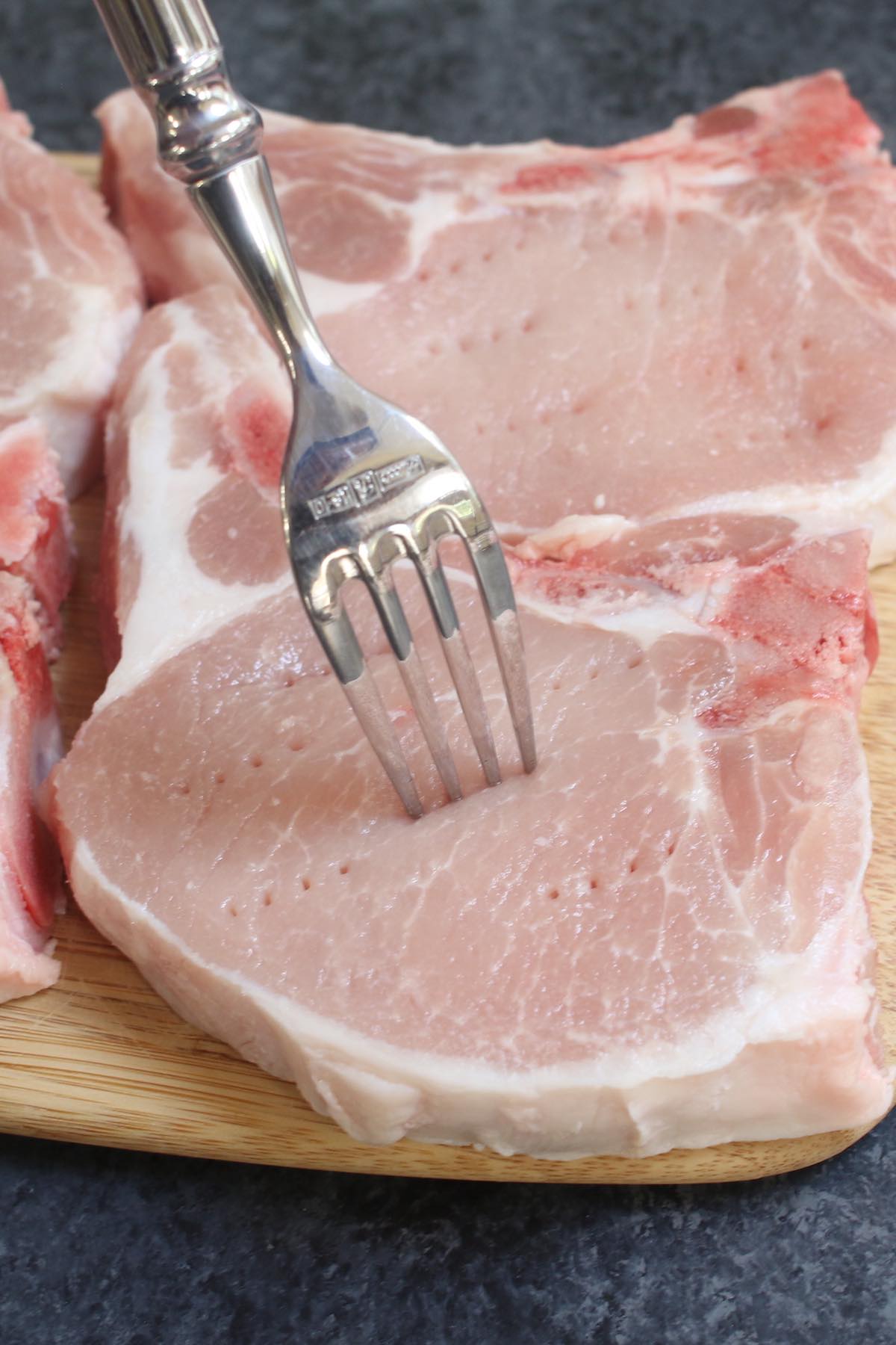 Closeup of piercing the pork chops with a fork.