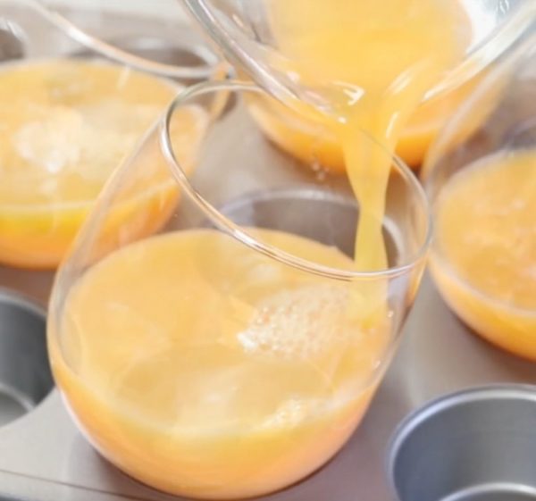 Closeup of pouring the mango puree into stemless wine glasses when making mango panna cotta