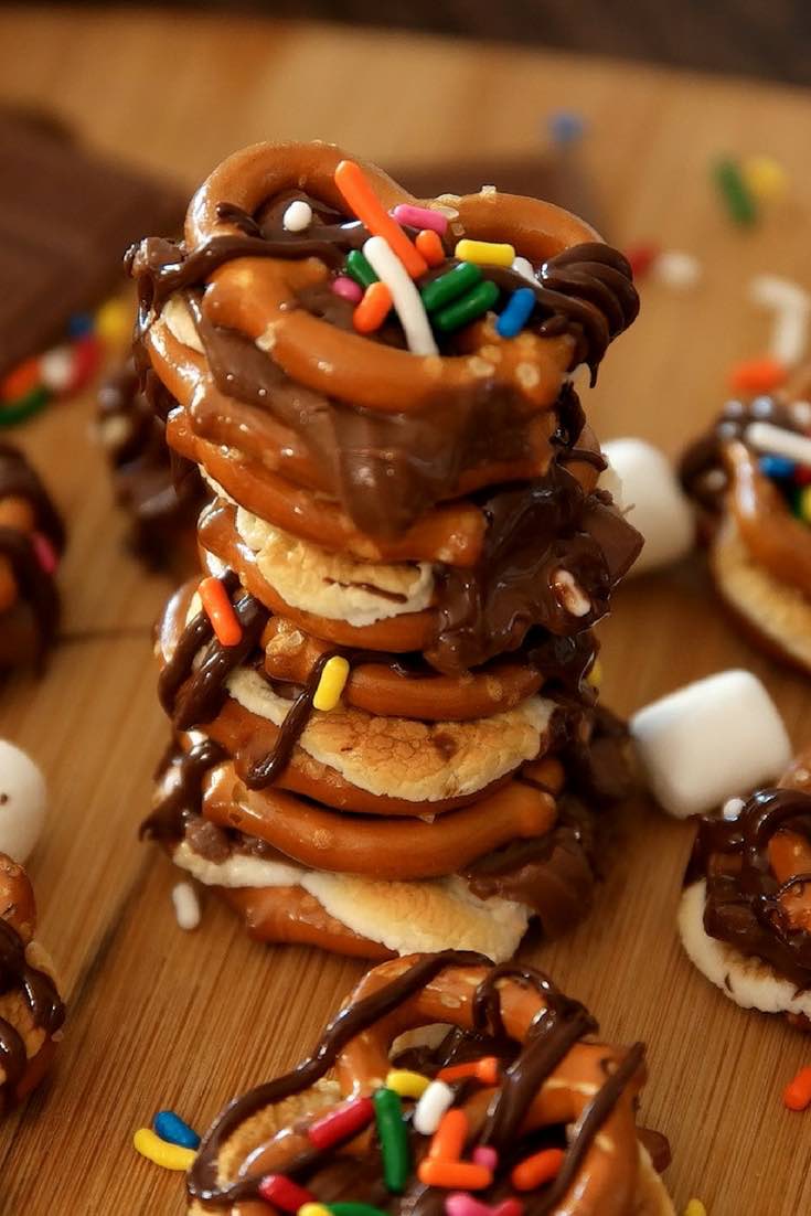 A stack of pretzel s'mores bites drizzled with chocolate sauce and with sprinkles on top