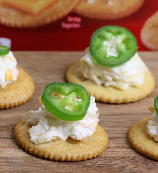 Jalapeno popper toppers made with jalapeno slices on top of Ritz cracker with a mixture of cream cheese and shredded cheese