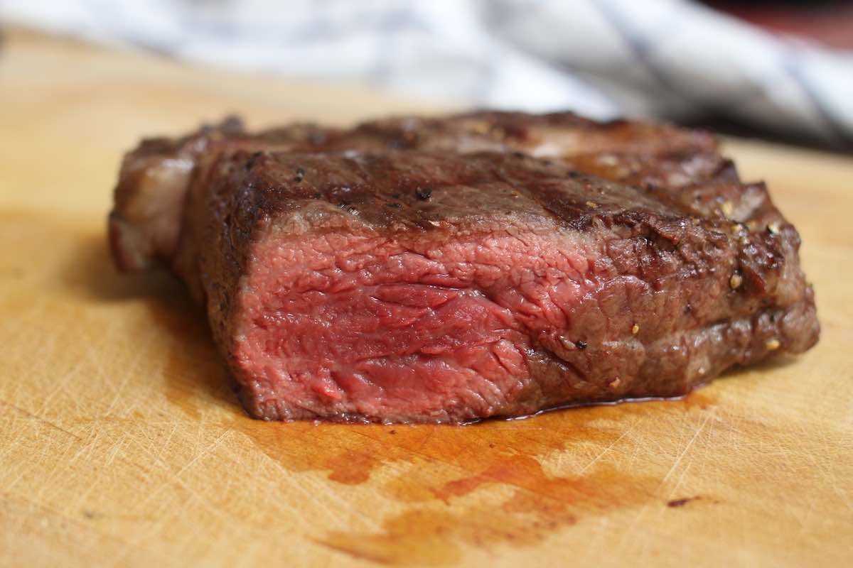 Closeup view of rare steak showing a brown, seared outside and red color on the inside
