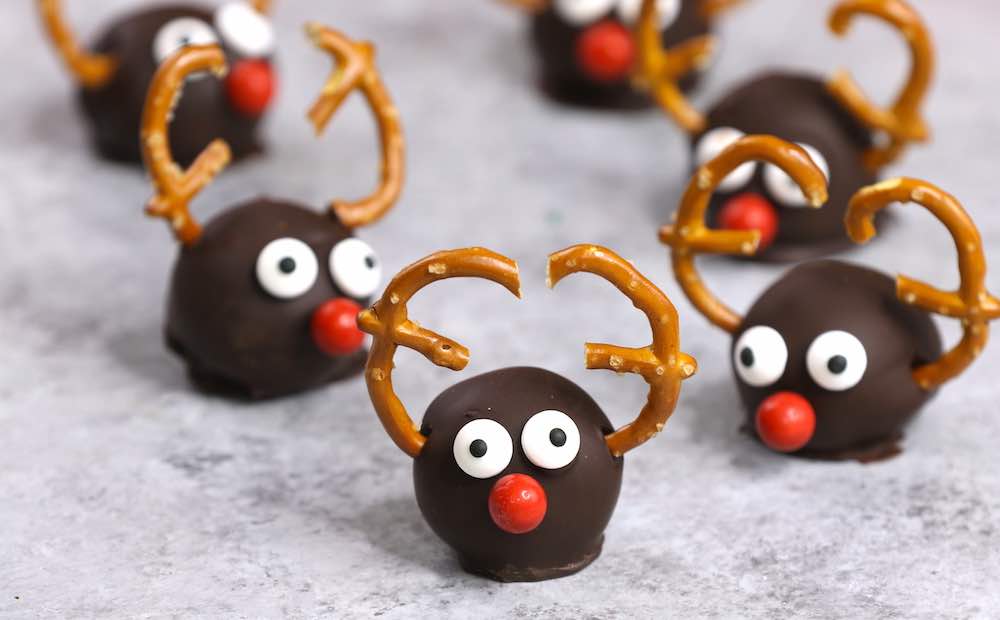 Reindeer Oreo Truffles consist of oreo cheesecake balls coated in dark chocolate and decorated in a reindeer theme for a cute holiday party treat or gift idea