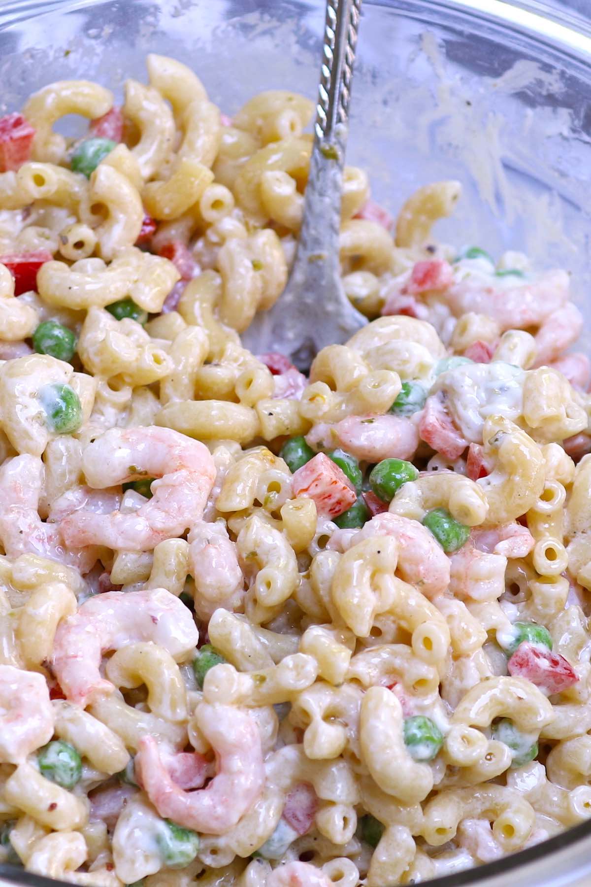 Tossing cooked macaroni with seafood and vegetables in an Italian dressing