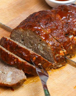 Perfect smoked meatloaf being sliced on a carving board