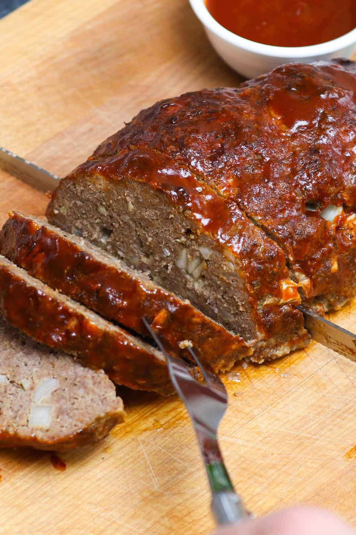 Smoked meatloaf on a carving board with barbecue sauce