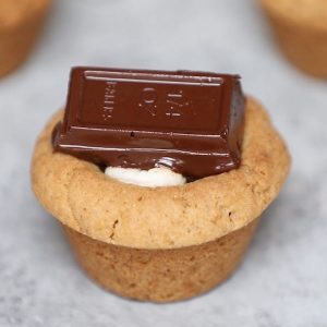 S’mores Cookie Cups – The perfect s’mores recipe that’s one of my favorite! Hot Graham cracker cookie cups baked in mini muffin tin, filled with marshmallow, and then topped with semi-sweet Baker’s or Hershey’s chocolate bars, boiled to gooey perfection. They melt in your mouth! So Yummy! All you need is only a few simple ingredients. Fun recipe to make with kids. Quick and Easy recipe that takes only 25 minutes. Dessert, Party Food. Vegetarian. Video recipe. | Tipbuzz.com