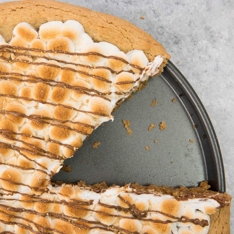 This photo shows Smores Pizza in a pizza pan after a piece has been served