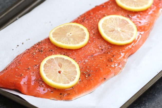 A fillet of seasoned sockeye on a baking sheet lined with parchment paper ready for cooking
