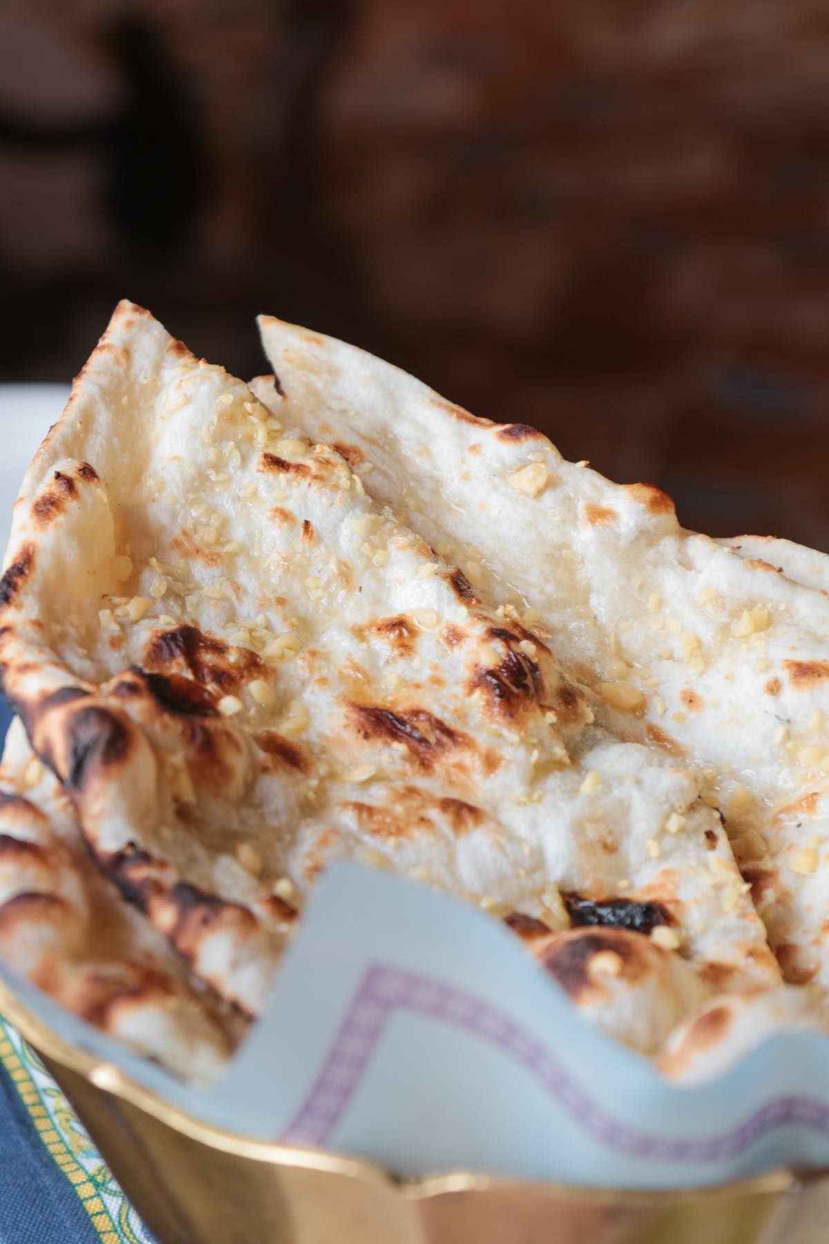 A basket of freshly made naan with golden minced garlic on top