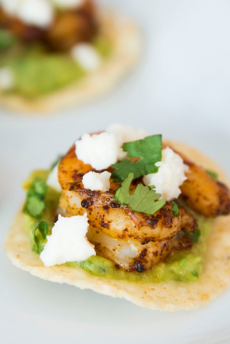 Mini Shrimp Tostadas garnished with queso fresco and fresh cilantro