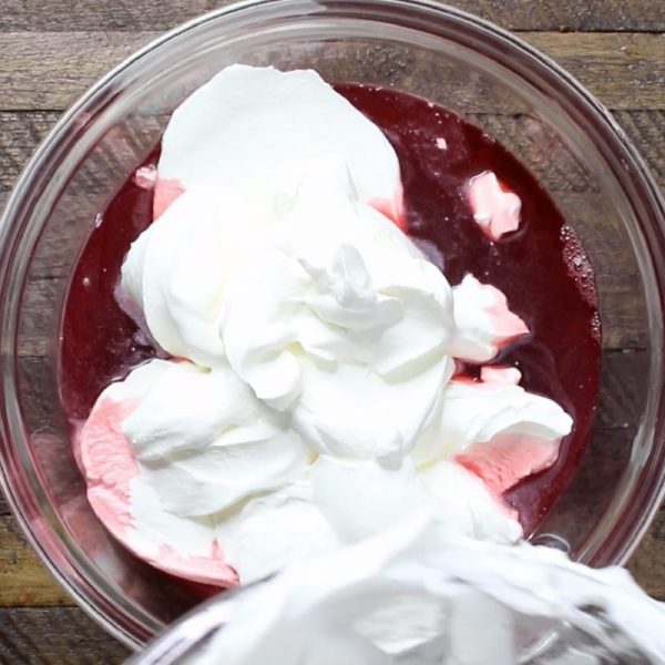 Mixing whipped cream into jello for strawberry jello cake