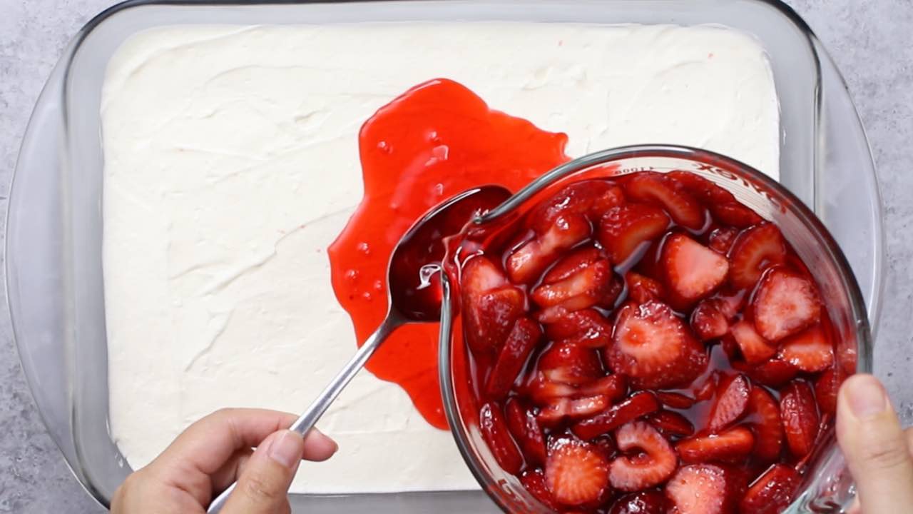 Strawberry Pretzel Salad: adding the strawberry jello layer on top of the smooth cream cheese layer in a rectangular baking pan