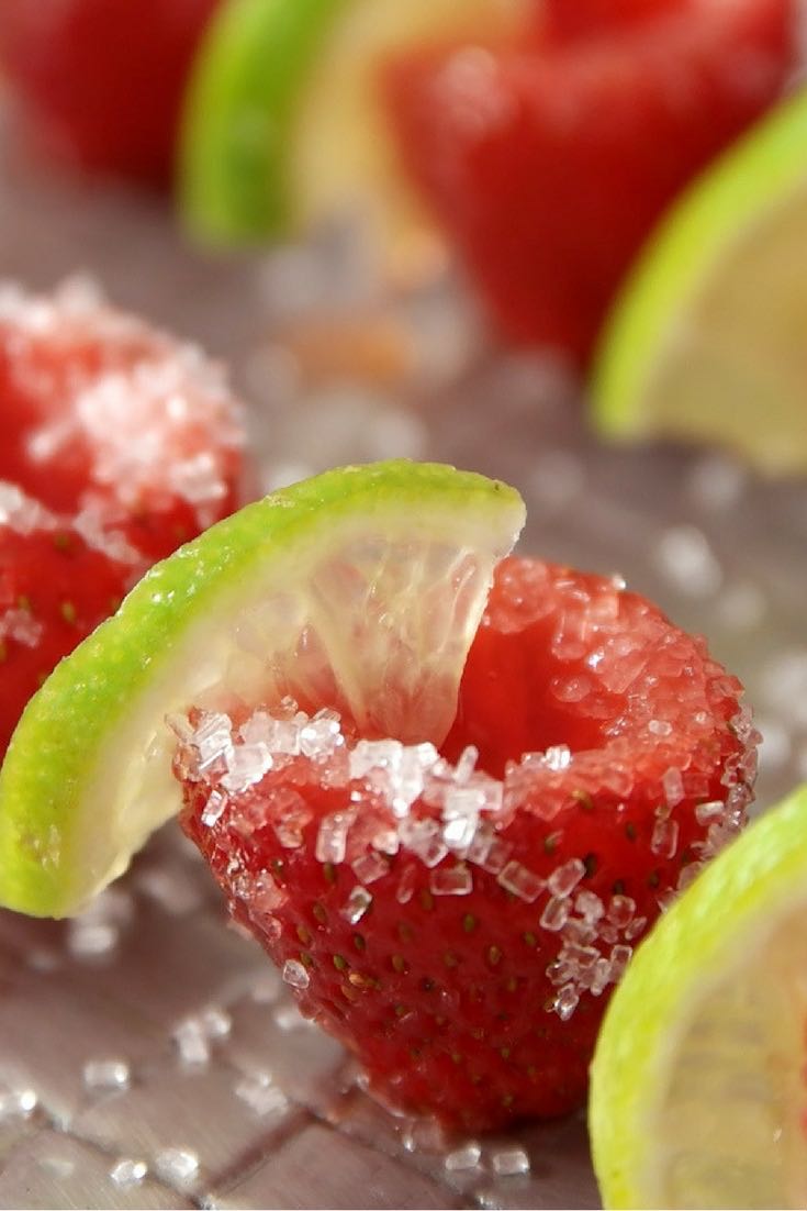 Here is a close-up view of a beautiful strawberry margarita jello shot served with a twist of lime on a plate