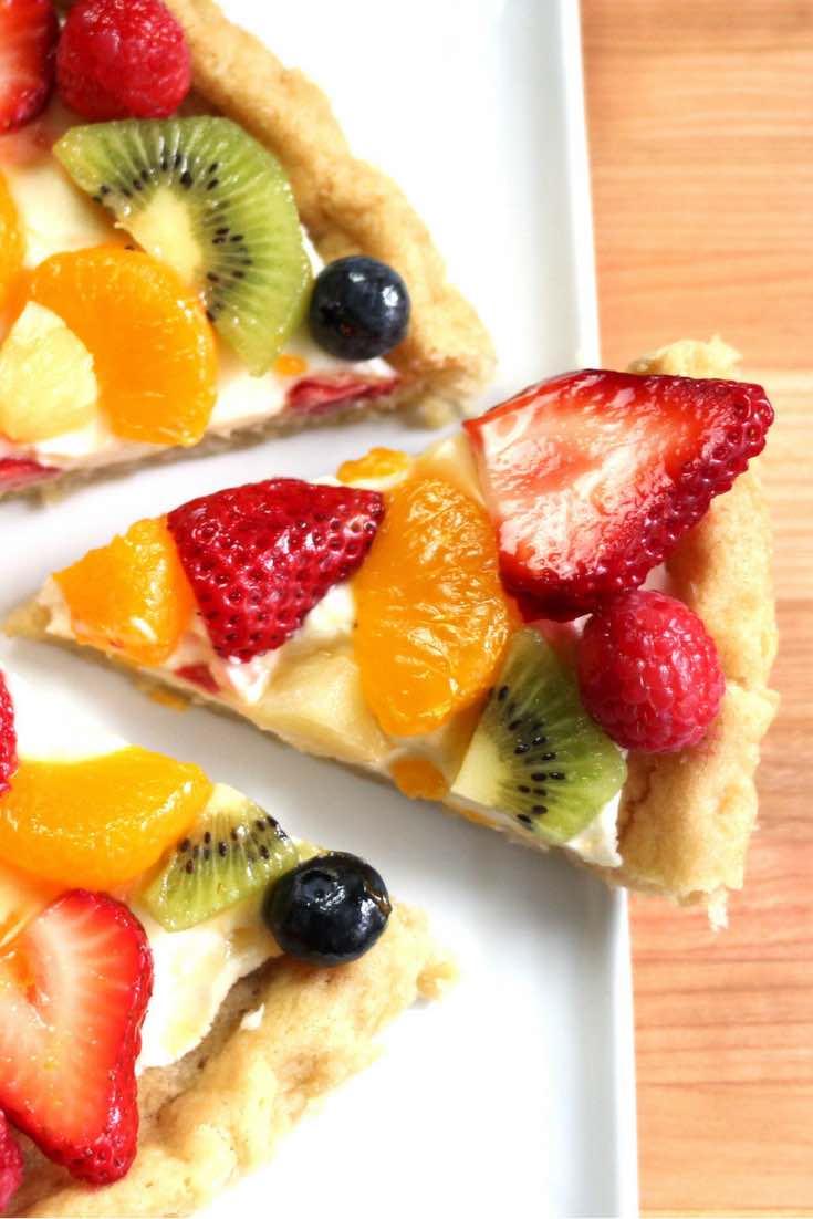 Fruity Pizza - The easiest and most unbelievably beautiful fruit pizza or fruity sugar cookie cake has a soft sugar cookie crust and smooth creamy filling, topped with fresh fruits. All you need is a few simple ingredients: refrigerated sugar cookie dough, cream cheese, sugar, vanilla extract and fruit of your choice! A simple dessert you whole family will be obsessed with. It takes only 20 minutes to make. Perfect for holiday party dessert such as Easter, Mother’s Day, Father’s Day or birthdays. Quick and easy, vegetarian. Video recipe. | tipbuzz.com