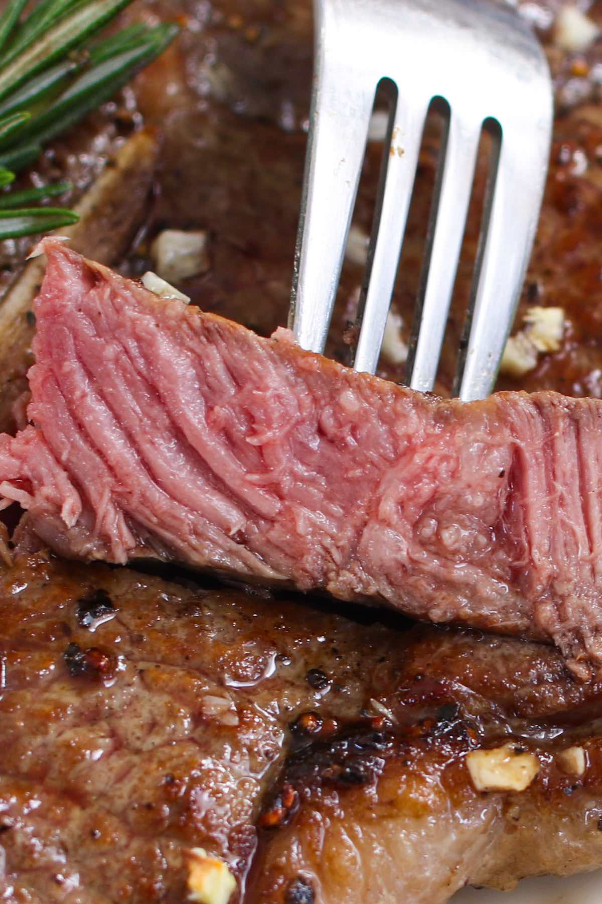 Cross-section view of a fork with piece of juicy t-bone steak cooked medium rare