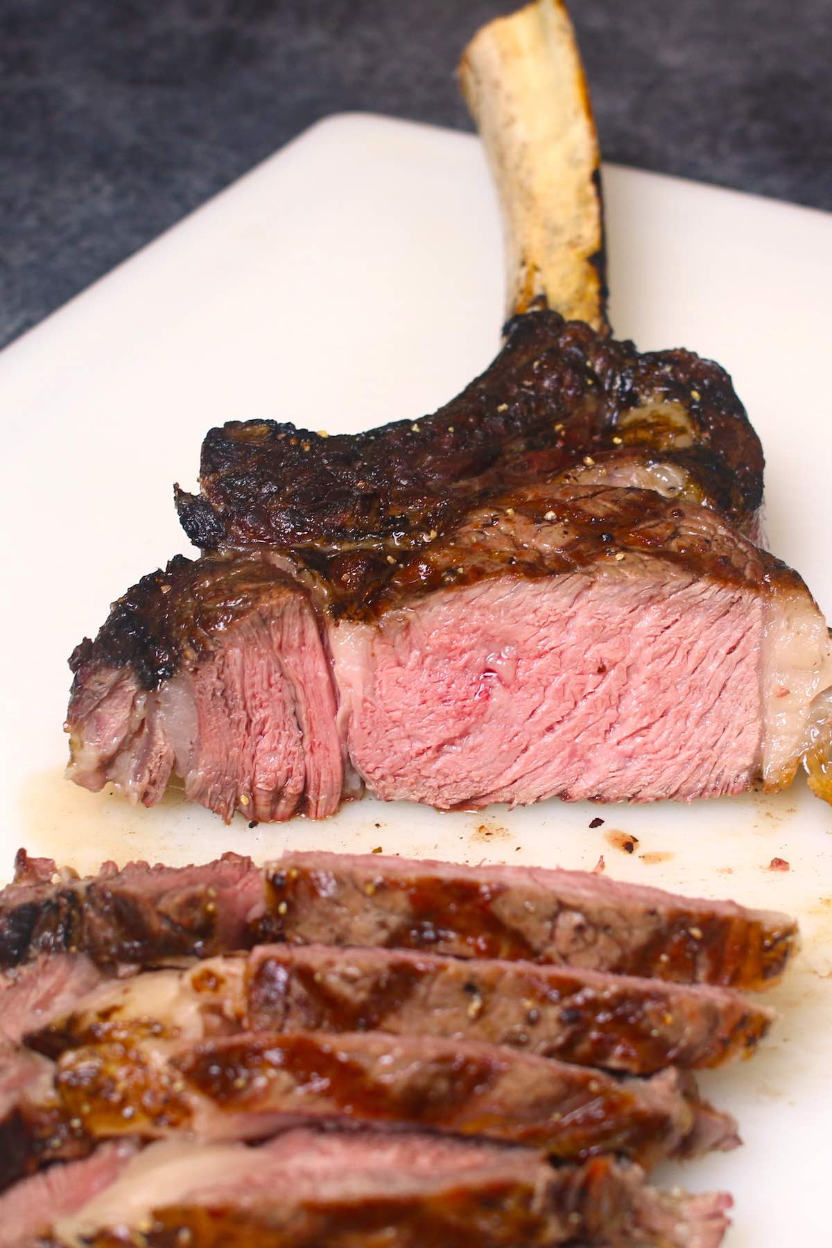 Tomahawk steak cooked medium and cut crosswise against the grain showing a warm pink color