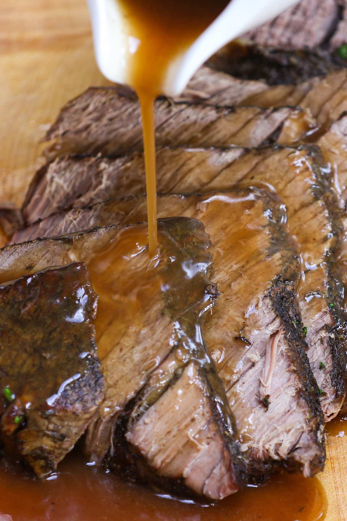 Pouring gravy onto slices of london broil Slices of london broil