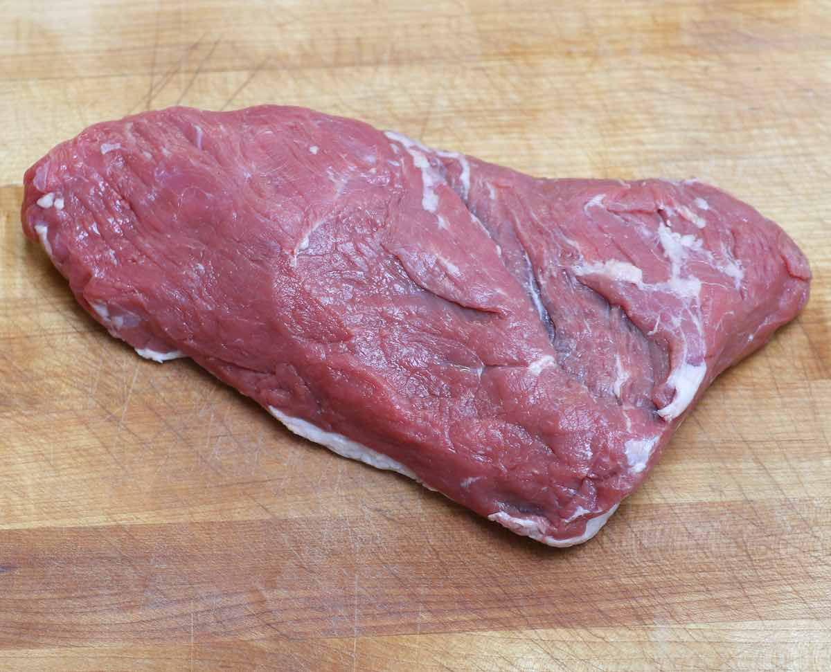 An uncooked tri tip steak on a cutting board