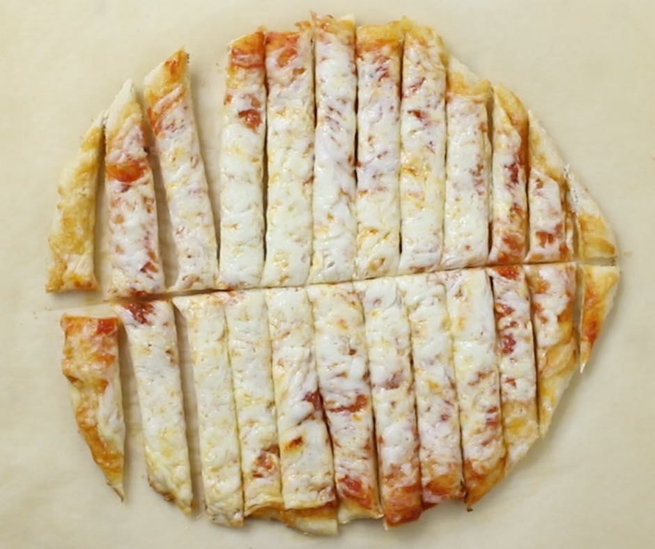 Cutting up a cheese pizza to make witch fingers