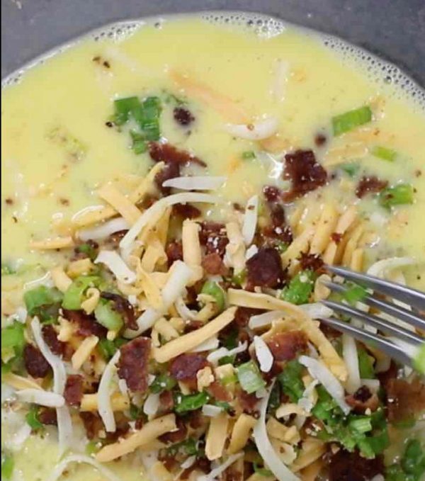 Mixing beaten eggs, crumbled bacon, shredded cheese and green onion in a mixing bowl