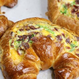 Breakfast Croissant Boats – crispy bacon, fluffy egg and melted cheddar cheese baked in croissant breakfast boats! A quick and easy recipe that’s ready in 30 minutes and feeds a crowd! Perfect for breakfast and brunch. So delicious! Video recipe. | Tipbuzz.com