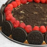 The Ultimate Oreo Cheesecake – the easiest and most beautiful cake topped with cookies and cream crumbs and fresh raspberries. All you need is a few simple ingredients: oreo cookies, cream cheese, sugar, vanilla, eggs, sour cream and raspberries. Great for dessert, brunch, birthday parties or Mother’s Day. Video recipe. | tipbuzz.com