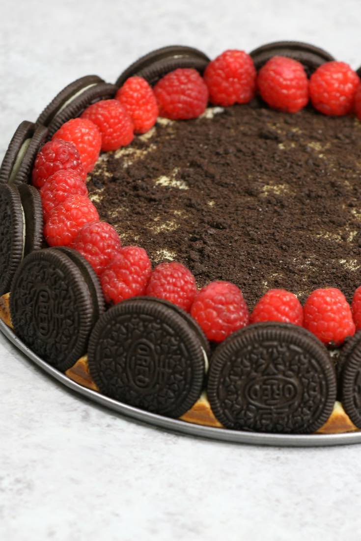 The Ultimate Oreo Cheesecake – the easiest and most beautiful cake topped with cookies and cream crumbs and fresh raspberries. All you need is a few simple ingredients: oreo cookies, cream cheese, sugar, vanilla, eggs, sour cream and raspberries. Great for dessert, brunch, birthday parties or Mother’s Day. Video recipe. | tipbuzz.com