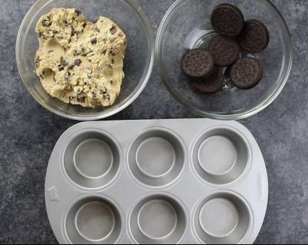 A muffin pan with a bowl of cookie dough and another bowl of oreos