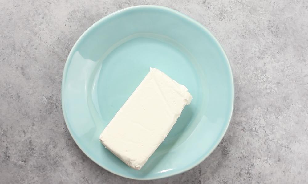 An 8 ounce brick of cream cheese that requires softening before use in recipes such as cheesecake or cheese dips